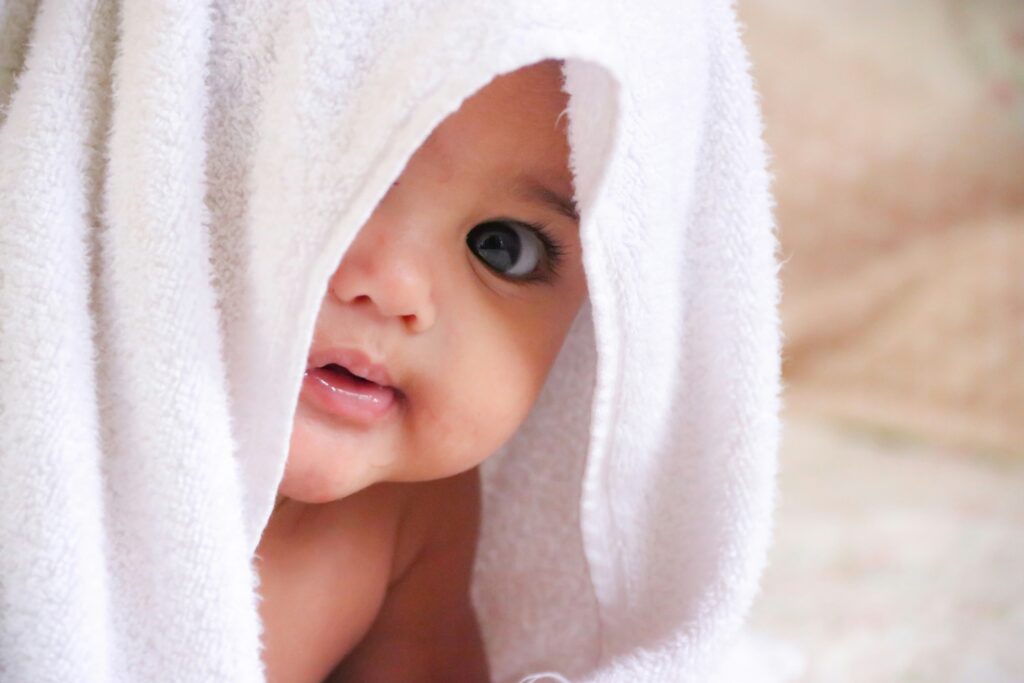 Mãe enrolando o bebê em uma toalha com capuz após o banho.